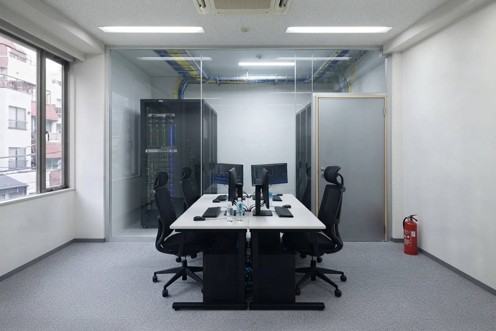 ELVIN の開発室。全席にモニタが2枚並び、ガラスの間仕切りの向こうにサーバーラックが4本見える
